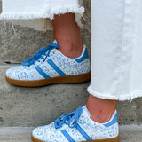 Blue floral sneakers with blue laces, side stripes, and tan rubber sole