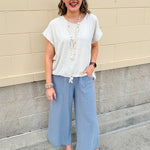 Linen-cotton blend short-sleeve top with front tie and raw hem in a soft neutral oatmeal shade.