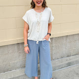 Linen-cotton blend short-sleeve top with front tie and raw hem in a soft neutral oatmeal shade.