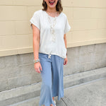 Linen-cotton blend short-sleeve top with front tie and raw hem in a soft neutral oatmeal shade.