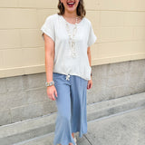 Linen-cotton blend short-sleeve top with front tie and raw hem in a soft neutral oatmeal shade.