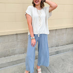 Linen-cotton blend short-sleeve top with front tie and raw hem in a soft neutral oatmeal shade.