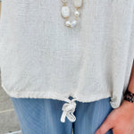 Linen-cotton blend short-sleeve top with front tie and raw hem in a soft neutral oatmeal shade.