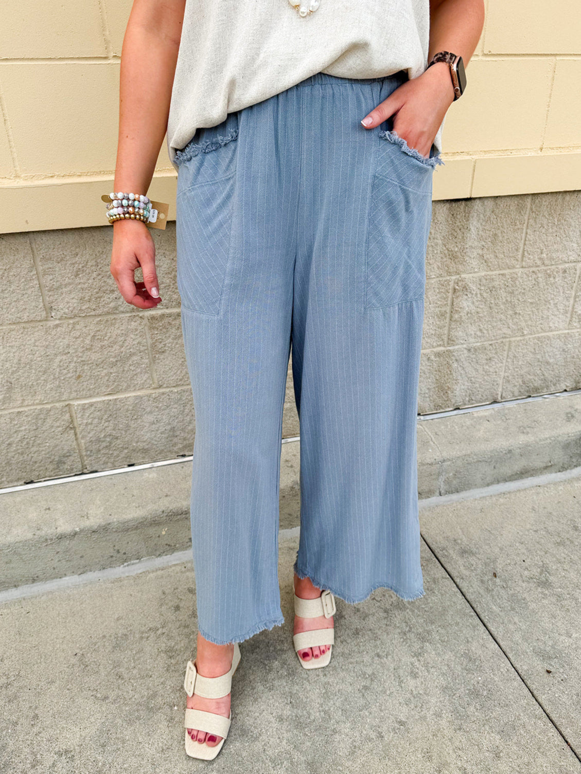 Light blue striped linen blend wide-leg pants with elastic waist, front pockets, and frayed details for an easy, relaxed fit.