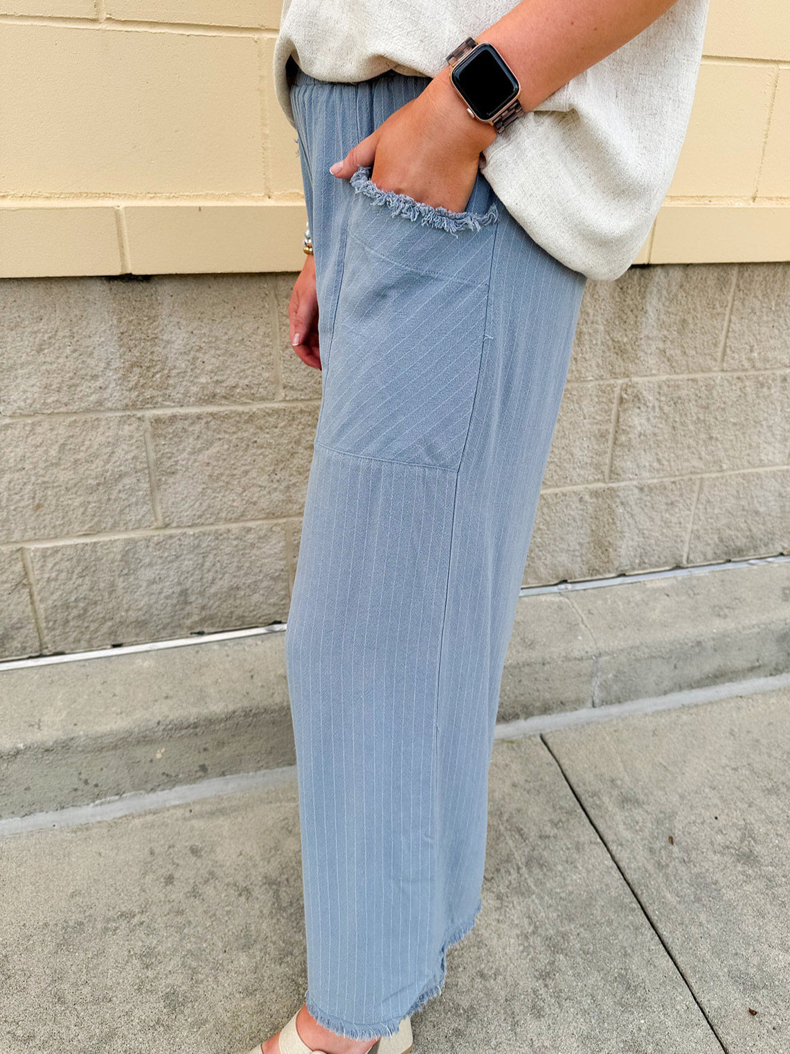 Light blue striped linen blend wide-leg pants with elastic waist, front pockets, and frayed details for an easy, relaxed fit.