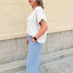 Linen-cotton blend short-sleeve top with front tie and raw hem in a soft neutral oatmeal shade.