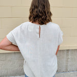 Linen-cotton blend short-sleeve top with front tie and raw hem in a soft neutral oatmeal shade.