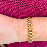 Gold watch band bracelet with clip clasp on neutral background