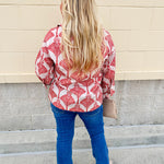 Cream shirt with rust pattern, collar, one button, and ¾-length cuffed sleeves