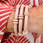 Minimalist skinny tube bracelet with metal bead accents, styled in a layered stack on a neutral-toned wrist display