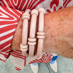 Minimalist skinny tube bracelet with metal bead accents, styled in a layered stack on a neutral-toned wrist display