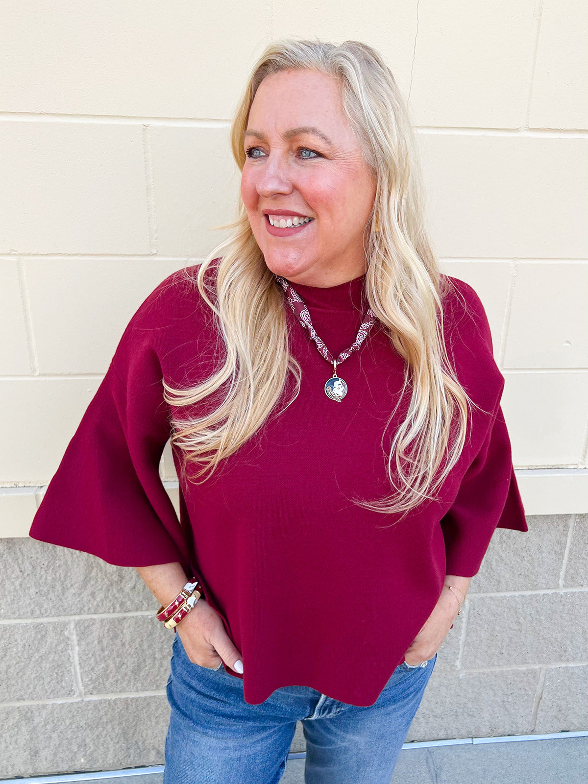 Wine-colored long-sleeve sweater with bell sleeves, ribbed neckline, and high-low hem.