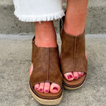 Chocolate brown vegan leather wedge with strap-back peep toe, open side slits, and raffia wedge bottom