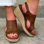 Chocolate brown vegan leather wedge with strap-back peep toe, open side slits, and raffia wedge bottom
