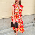 Collared midi dress with red, cream, and green pattern, ruffle sleeves, and buttons down front