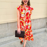 Collared midi dress with red, cream, and green pattern, ruffle sleeves, and buttons down front