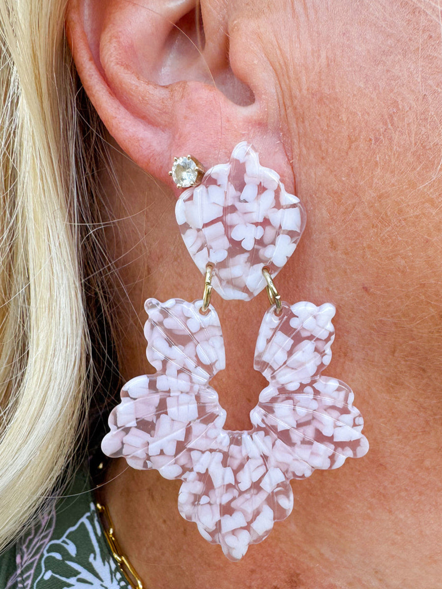 Close-up of a person wearing pink floral earrings with a blurred background
