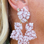Close-up of a person wearing pink floral earrings with a blurred background