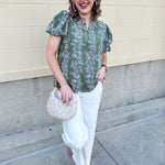 Green floral top with white and pink flowers, short sleeves, and V-neckline