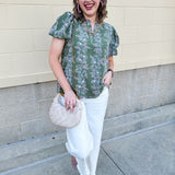Green floral top with white and pink flowers, short sleeves, and V-neckline
