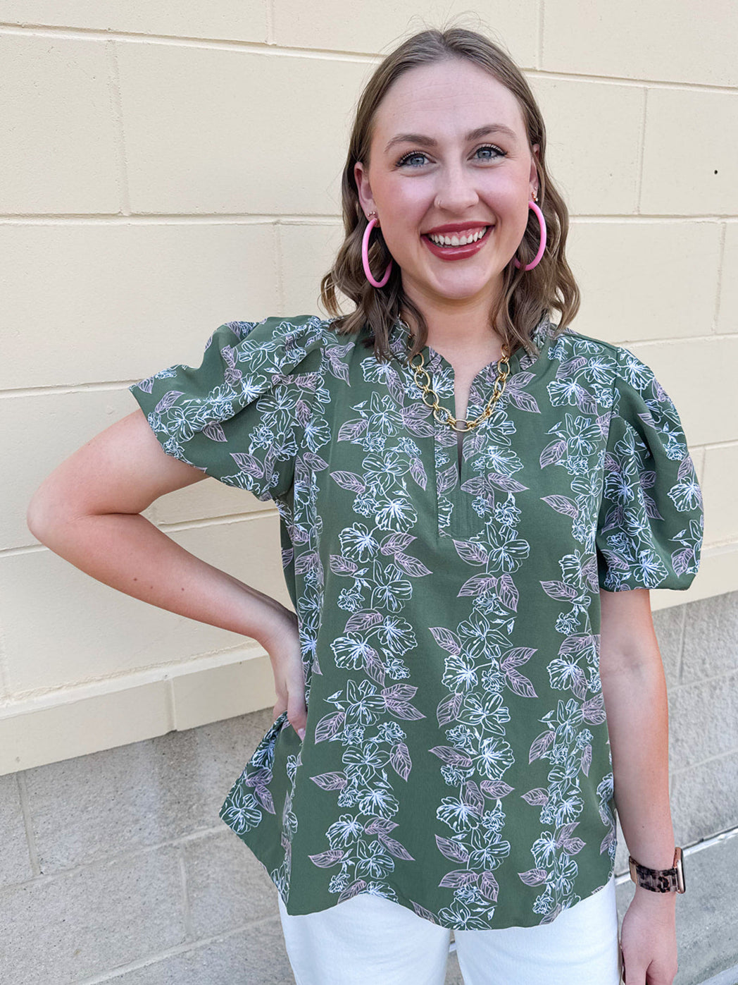Green floral top with white and pink flowers, short sleeves, and V-neckline