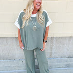 Sage green ribbed lounge pants with white waistband, drawstring, and large front patch pockets in a straight-leg fit