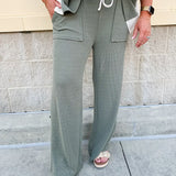 Sage green ribbed lounge pants with white waistband, drawstring, and large front patch pockets in a straight-leg fit