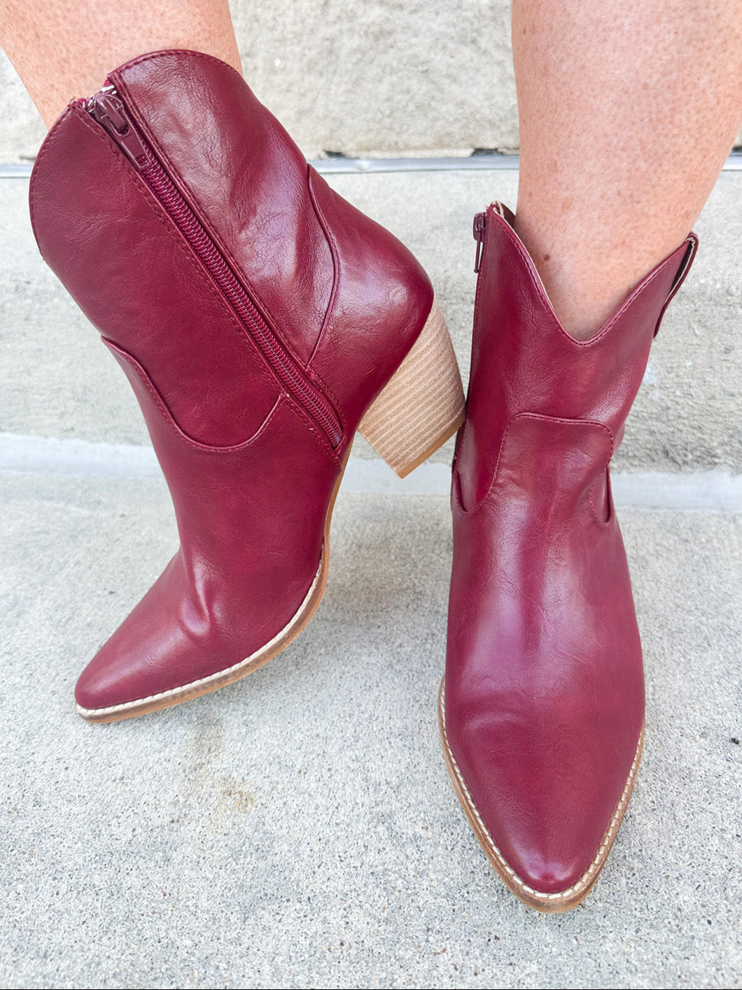 Garnet-hued western ankle boots with a pointed toe, stacked leather heel, and pull-on tabs.