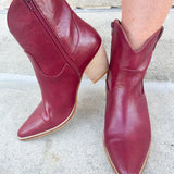 Garnet-hued western ankle boots with a pointed toe, stacked leather heel, and pull-on tabs.