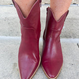 Garnet-hued western ankle boots with a pointed toe, stacked leather heel, and pull-on tabs.