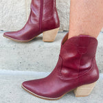Garnet-hued western ankle boots with a pointed toe, stacked leather heel, and pull-on tabs.