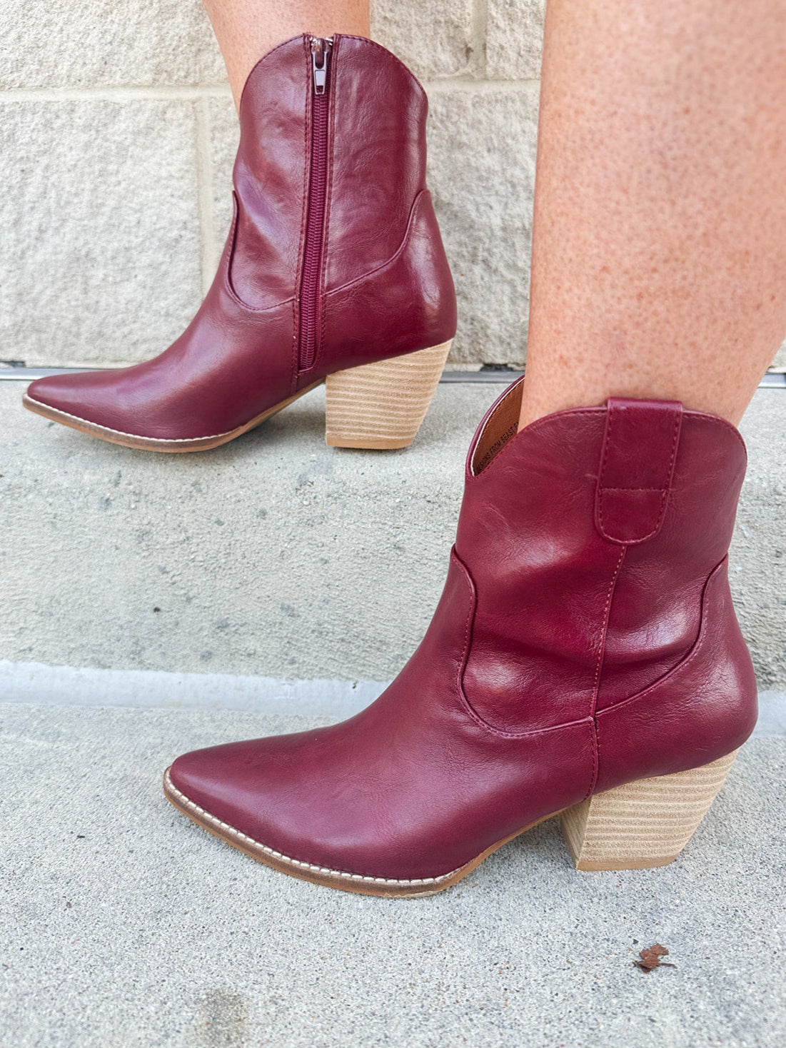 Garnet-hued western ankle boots with a pointed toe, stacked leather heel, and pull-on tabs.