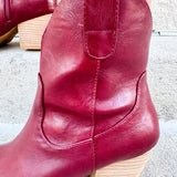 Garnet-hued western ankle boots with a pointed toe, stacked leather heel, and pull-on tabs.