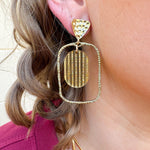 Gold oval hoop earrings with a striped textured design.