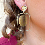 Gold oval hoop earrings with a striped textured design.