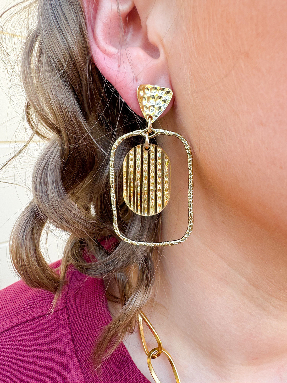 Gold oval hoop earrings with a striped textured design.