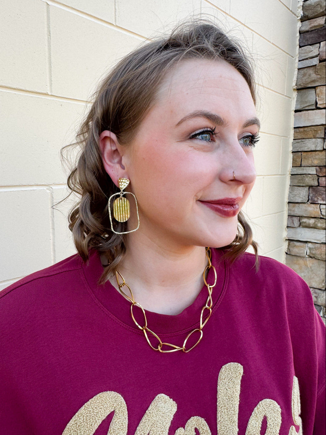 Gold oval hoop earrings with a striped textured design.
