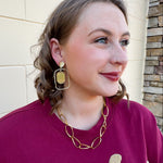Gold oval hoop earrings with a striped textured design.