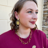 Gold oval hoop earrings with a striped textured design.