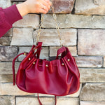 Deep garnet faux leather slouchy shoulder bag with gold chain straps and drawstring-style closure.