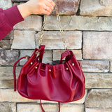 Deep garnet faux leather slouchy shoulder bag with gold chain straps and drawstring-style closure.