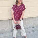Garnet rolled cuff blouse with allover gold spear pattern, short sleeves, and boxy fit.
