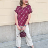 Garnet rolled cuff blouse with allover gold spear pattern, short sleeves, and boxy fit.