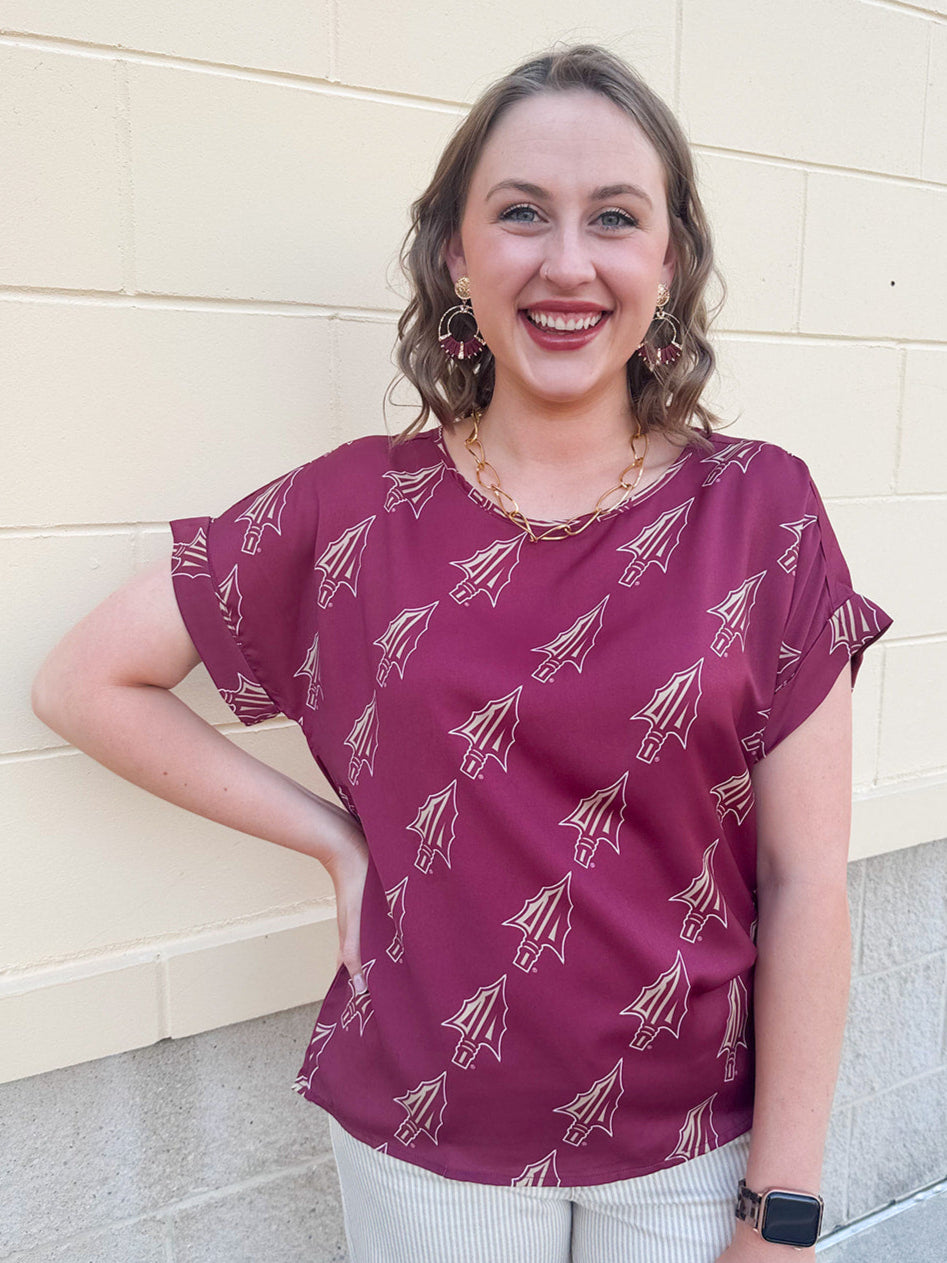 Garnet rolled cuff blouse with allover gold spear pattern, short sleeves, and boxy fit.
