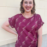 Garnet rolled cuff blouse with allover gold spear pattern, short sleeves, and boxy fit.