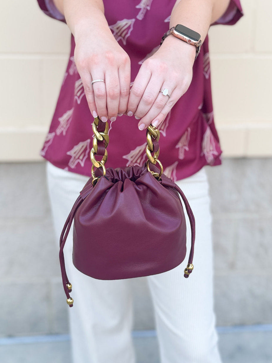 Garnet faux leather mini drawstring purse with chainlink handle woven with leather.