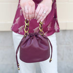 Garnet faux leather mini drawstring purse with chainlink handle woven with leather.