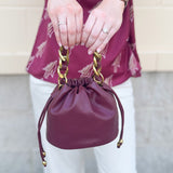 Garnet faux leather mini drawstring purse with chainlink handle woven with leather.