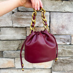 Garnet faux leather mini drawstring purse with chainlink handle woven with leather.