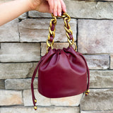 Garnet faux leather mini drawstring purse with chainlink handle woven with leather.